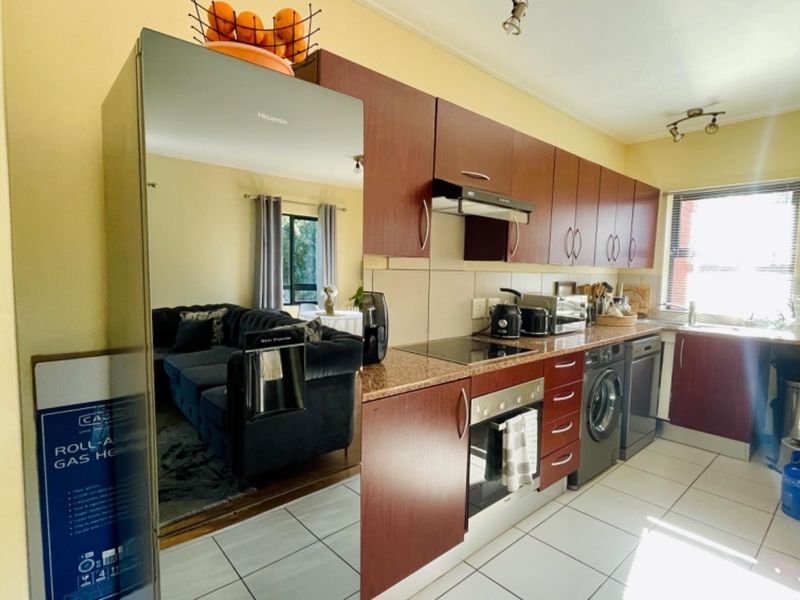 A functional kitchen featuring dark wood cabinetry, granite countertops, integrated appliances, and tiled flooring, offering a practical layout for daily cooking and preparation.