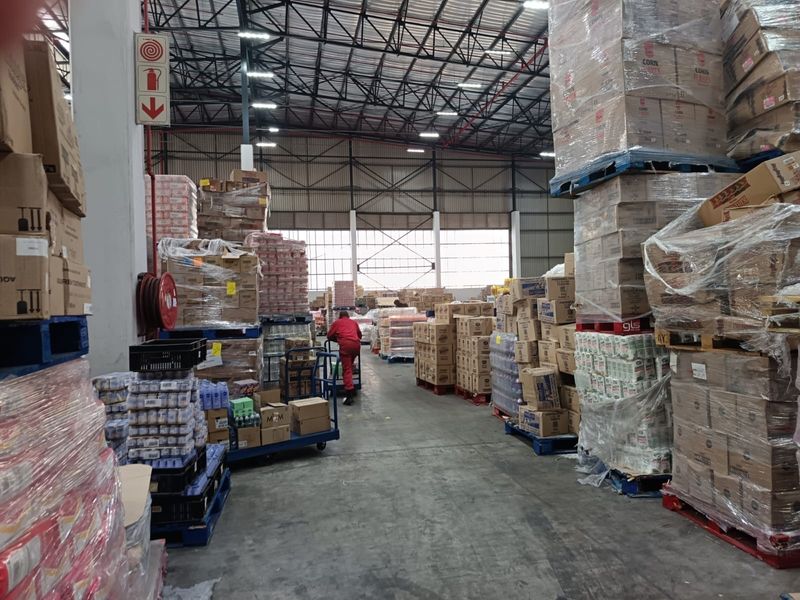 Spacious industrial warehouse facility featuring high-clearance ceilings, exposed steel trusses, and durable concrete flooring, currently utilized for bulk storage and logistics operations.