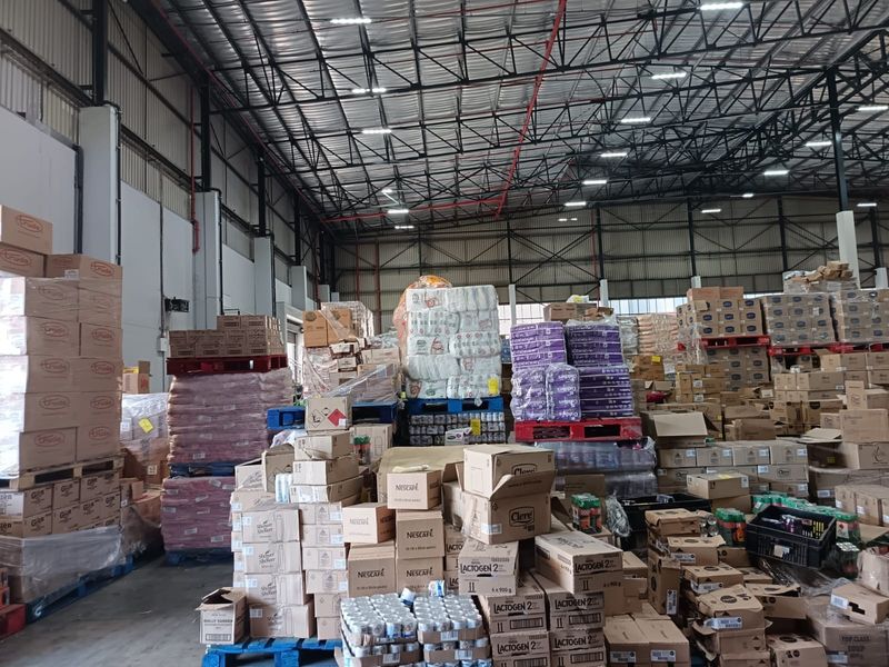 Large industrial warehouse space featuring high ceilings with exposed steel trusses, concrete flooring, and integrated fire sprinkler systems.