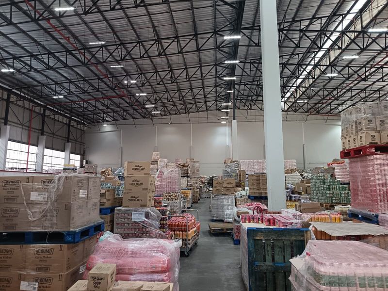 Spacious industrial warehouse facility featuring high ceilings with exposed steel trusses, concrete flooring, and integrated fire sprinkler systems.
