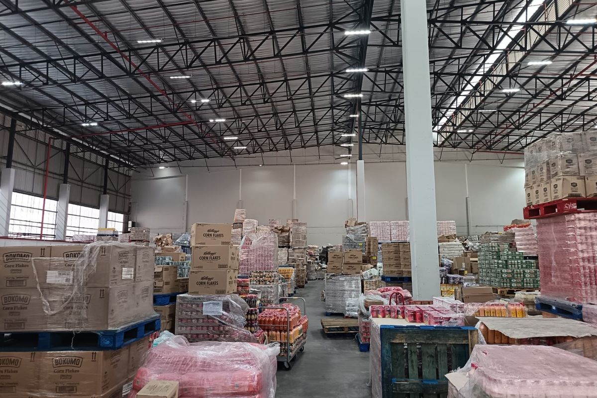 Spacious industrial warehouse facility featuring high ceilings with exposed steel trusses, concrete flooring, and integrated fire sprinkler systems.