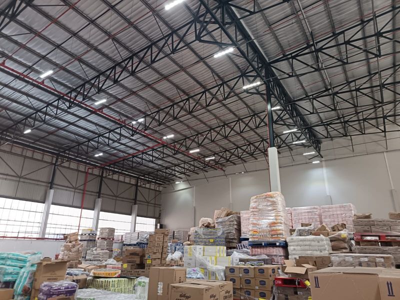 Spacious industrial warehouse featuring high-clearance ceilings with exposed steel trusses, integrated fire sprinkler system, and efficient LED lighting throughout the storage area.