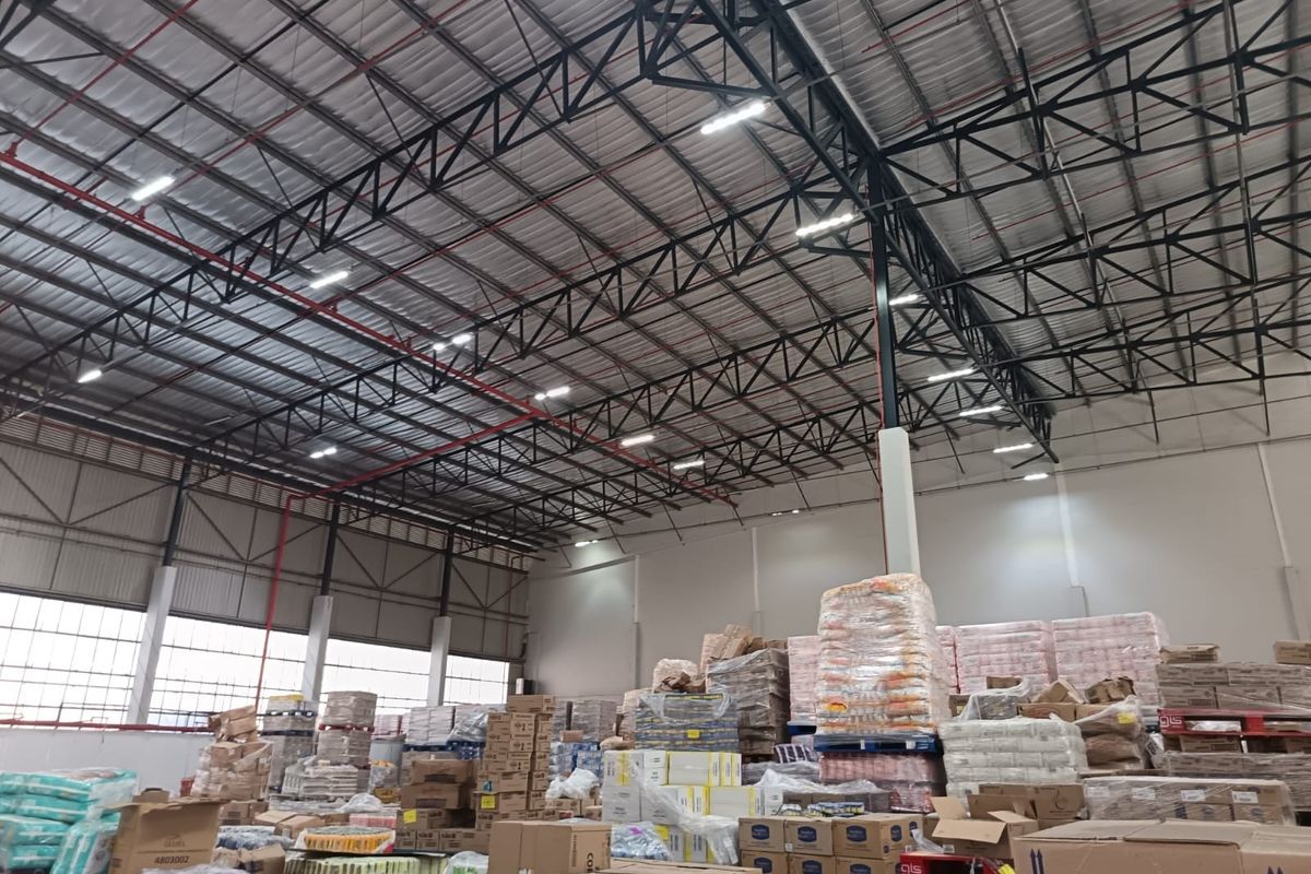 Spacious industrial warehouse featuring high-clearance ceilings with exposed steel trusses, integrated fire sprinkler system, and efficient LED lighting throughout the storage area.