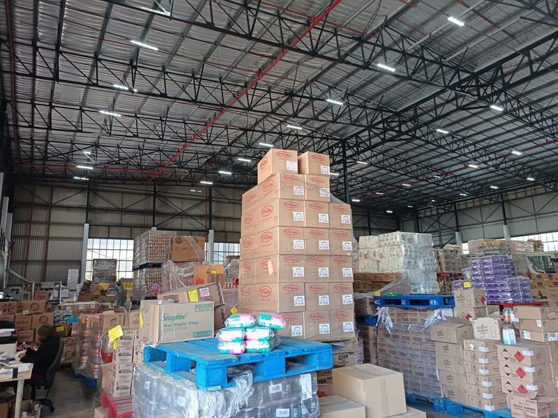 Spacious industrial warehouse featuring high-clearance exposed steel roof trusses, fire sprinkler systems, and durable concrete flooring, currently utilized for storage.
