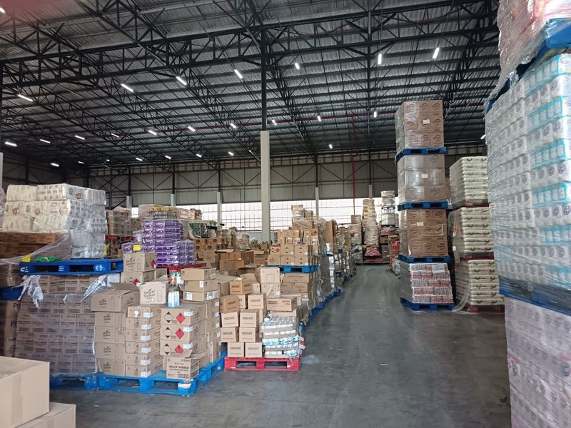 Spacious industrial warehouse facility featuring high-bay ceilings, exposed steel roof trusses, and durable concrete flooring, currently utilized for bulk storage.