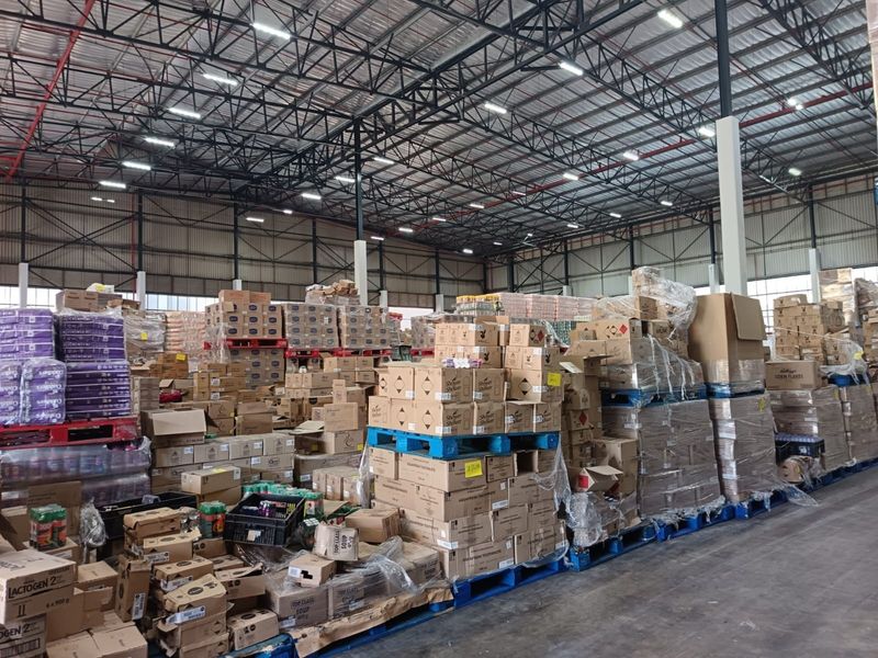 Large industrial warehouse space featuring high-clearance exposed steel truss roofing, concrete flooring, and an integrated fire sprinkler system.