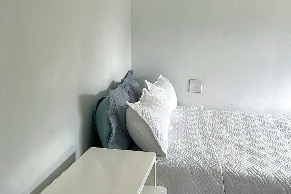 A simple bedroom featuring white walls and decorative ceiling cornicing.