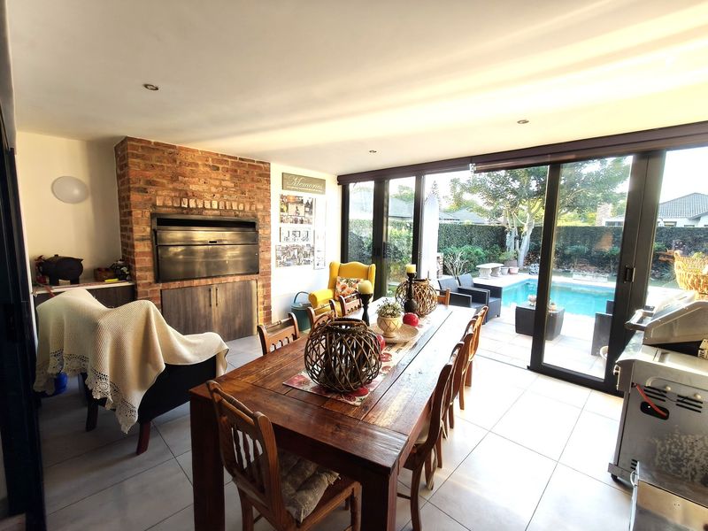 Open-plan living and dining area featuring a built-in brick fireplace and large sliding glass doors that open directly onto the pool patio.