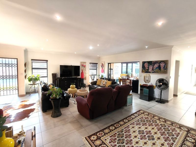 Spacious open-plan living area featuring tiled flooring, recessed downlighting, and large sliding glass doors providing access to the outdoor space.