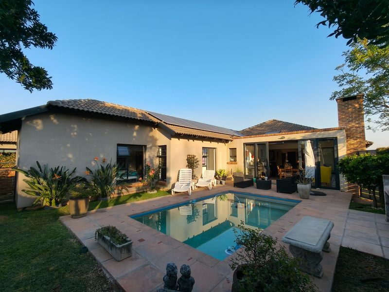 A well-maintained rear garden featuring a swimming pool with tiled surround, solar panels on the roof, and direct access to the home via sliding doors.