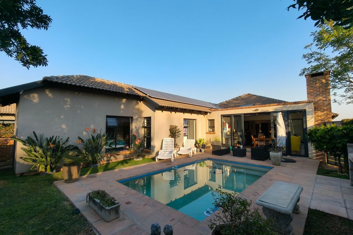 A well-maintained rear garden featuring a swimming pool with tiled surround, solar panels on the roof, and direct access to the home via sliding doors.