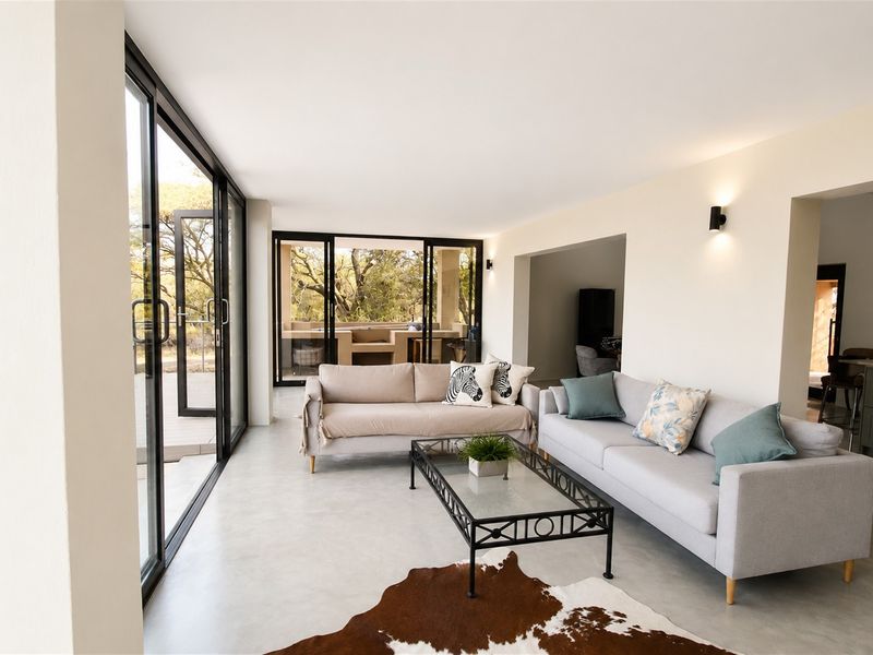 Bright open-plan living area featuring polished concrete floors and large sliding glass doors that provide seamless access to the outdoor patio space.