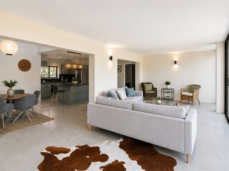 Spacious open-plan living and dining area featuring polished concrete floors, modern kitchen with island, and large sliding glass doors leading to the outdoors.