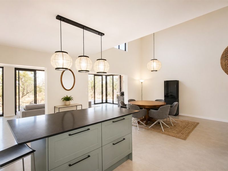 Spacious open-plan living and kitchen area featuring a central island, high ceilings, and large sliding glass doors that provide abundant natural light.