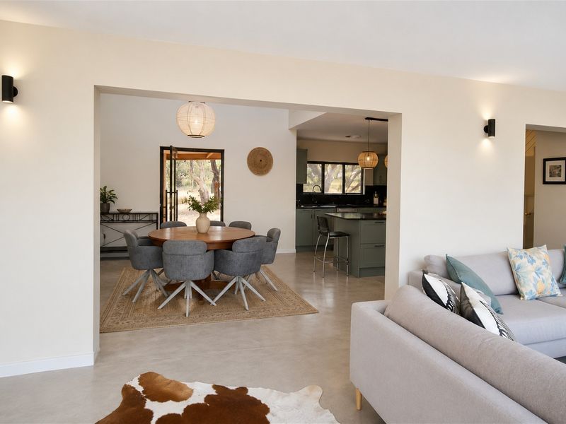 Spacious open-plan living and dining area featuring polished concrete floors, modern lighting, and a seamless transition to the kitchen and outdoor space.