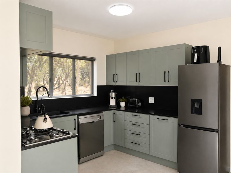 Modern kitchen featuring sage green cabinetry, black stone countertops, a gas hob, and integrated dishwasher, offering a clean and contemporary aesthetic.
