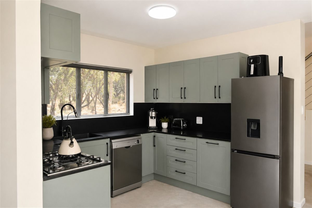 Modern kitchen featuring sage green cabinetry, black stone countertops, a gas hob, and integrated dishwasher, offering a clean and contemporary aesthetic.