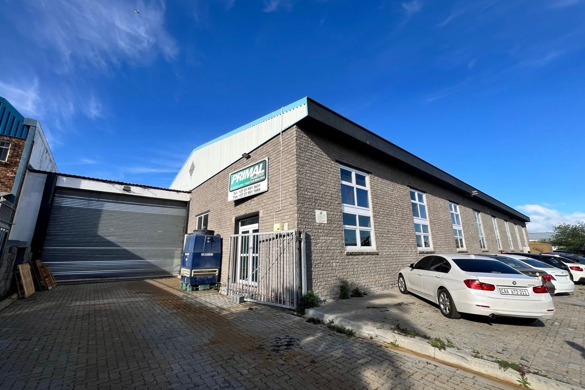 Industrial property exterior featuring a brick facade, roller shutter door, and paved driveway area suitable for commercial or warehouse operations.