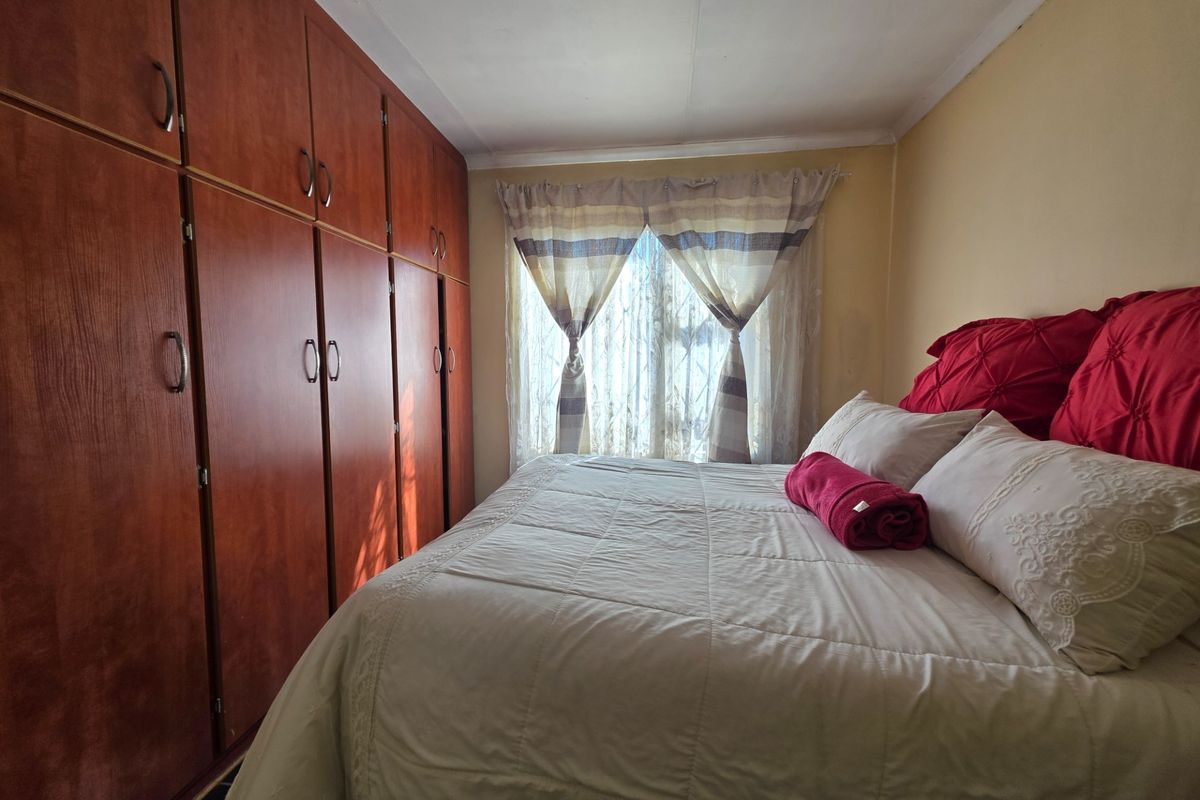 A bedroom featuring floor-to-ceiling built-in wooden cupboards and a window with natural light.