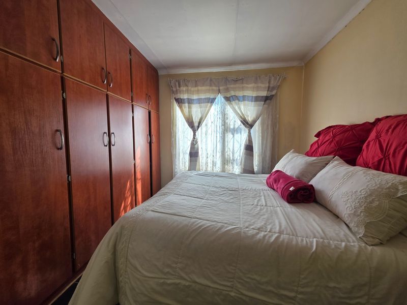 A bedroom featuring floor-to-ceiling built-in wooden cupboards and a window with natural light.