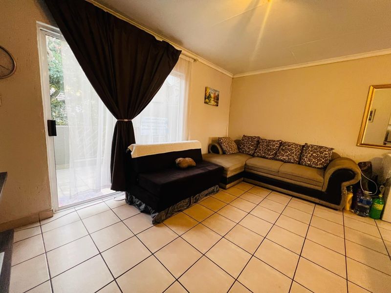 A living room featuring ceramic floor tiles and a sliding glass door providing access to an outdoor area.