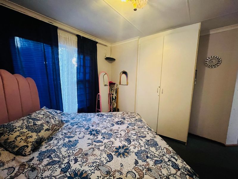 A bedroom featuring a built-in wardrobe and cove cornice detailing, requiring some cosmetic updates to the ceiling and flooring.