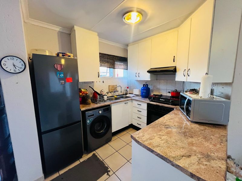 Compact kitchen featuring laminate countertops, white cabinetry, tiled backsplash, and integrated sink, offering a functional layout for an apartment setting.