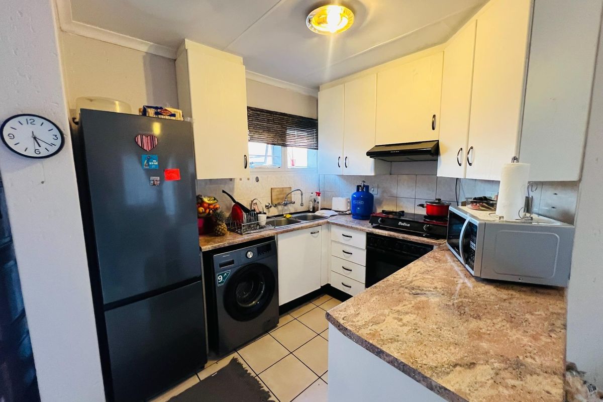 Compact kitchen featuring laminate countertops, white cabinetry, tiled backsplash, and integrated sink, offering a functional layout for an apartment setting.