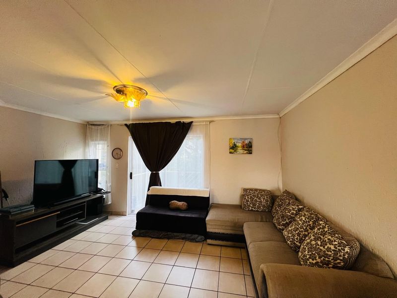 A living room featuring ceramic tiled flooring, a sliding glass door providing natural light, and standard ceiling finishes.