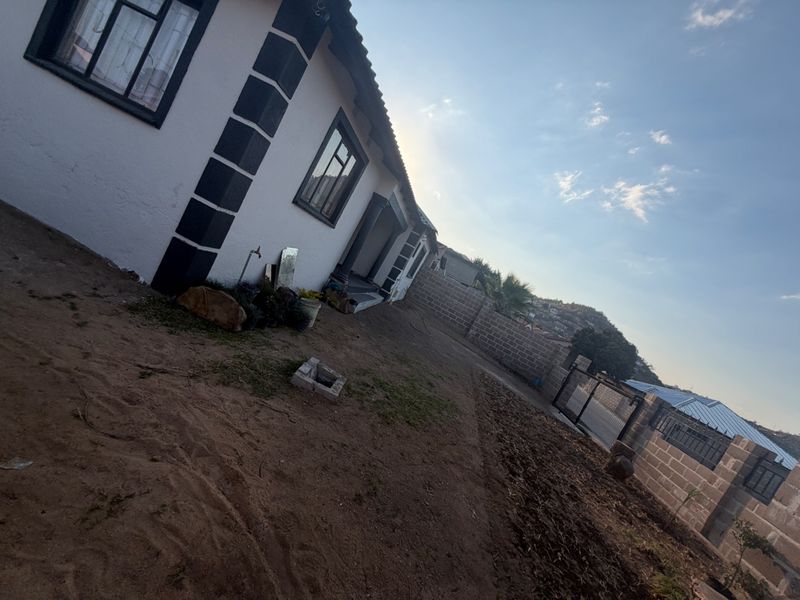 Rear exterior view of the property featuring a concrete block boundary wall, metal gate, and an unlandscaped yard area.