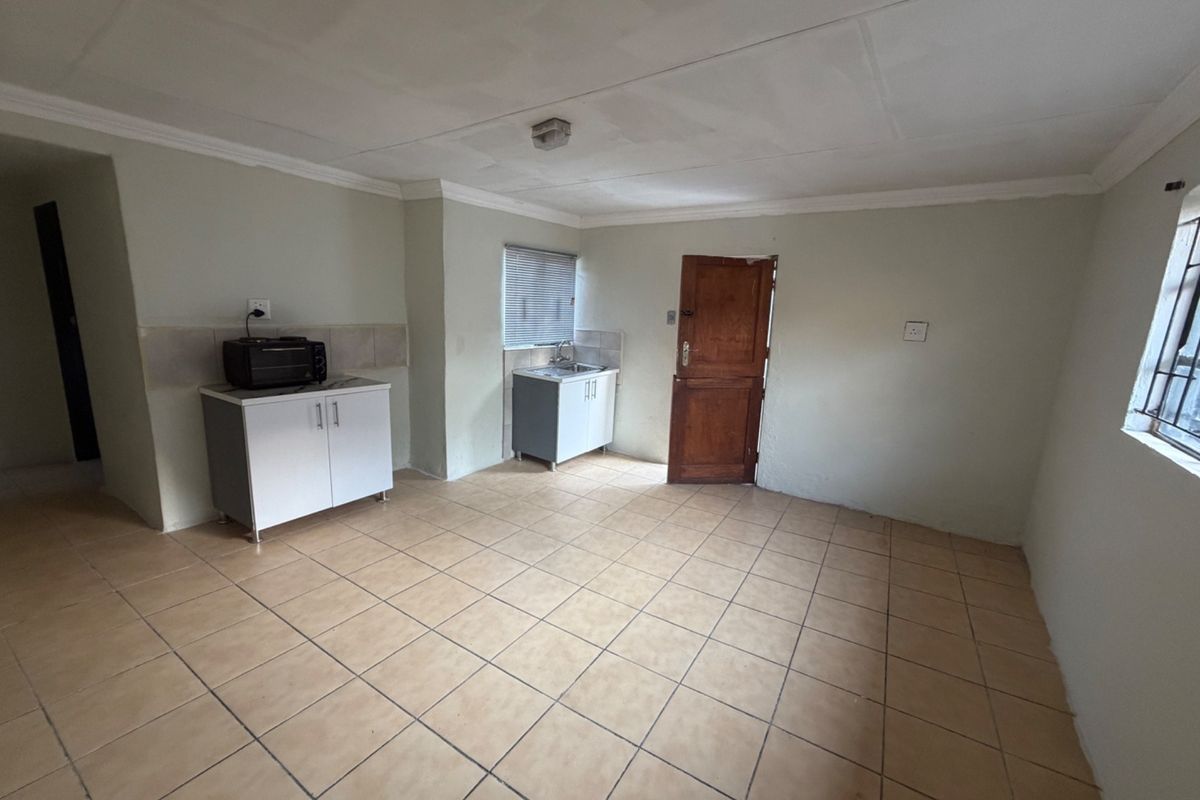 A basic, empty kitchen area featuring tiled flooring, simple cabinetry, and a sink, offering a blank canvas for potential renovation and modernization.