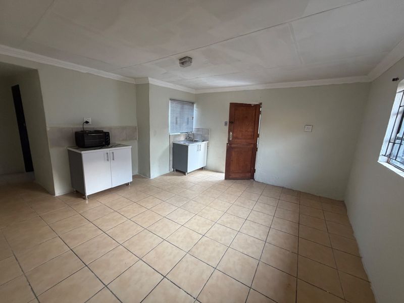 A basic, empty kitchen area featuring tiled flooring, simple cabinetry, and a sink, offering a blank canvas for potential renovation and modernization.