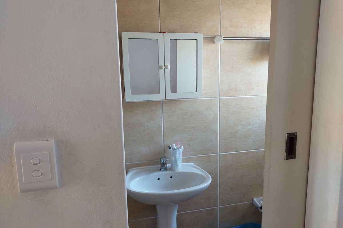 A functional bathroom featuring a pedestal basin, tiled walls, and a wall-mounted medicine cabinet.
