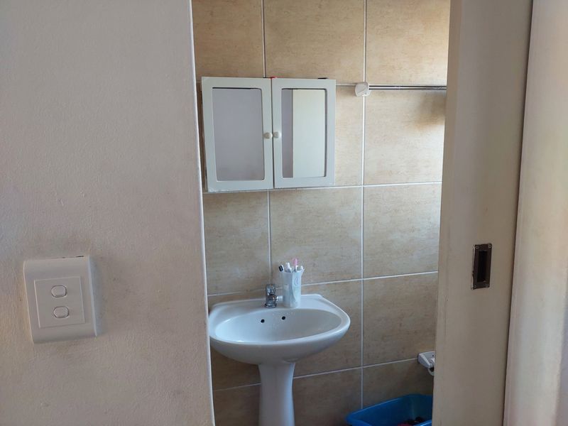 A functional bathroom featuring a pedestal basin, tiled walls, and a wall-mounted medicine cabinet.