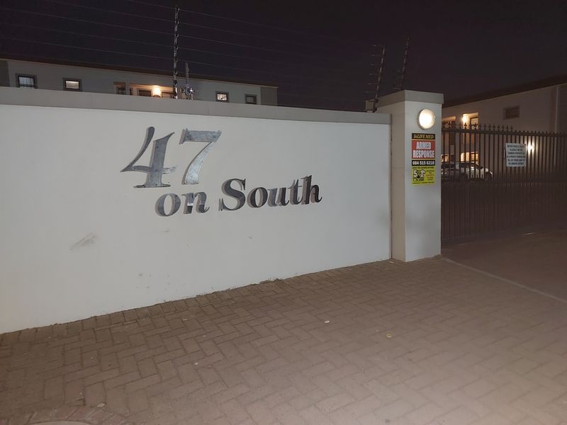 Night view of the entrance to 47 on South, featuring a secure boundary wall, electric fencing, and a gated access point.