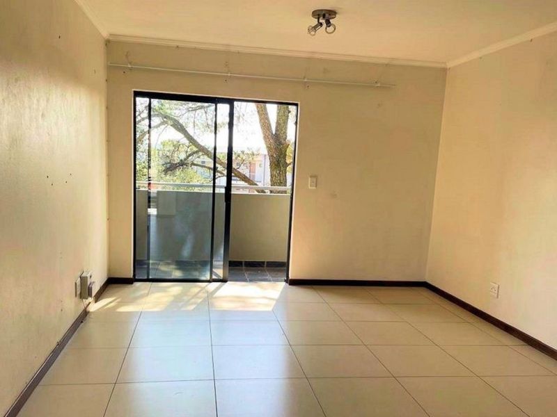 An empty living room featuring tiled flooring and a sliding glass door providing access to an outdoor balcony area.