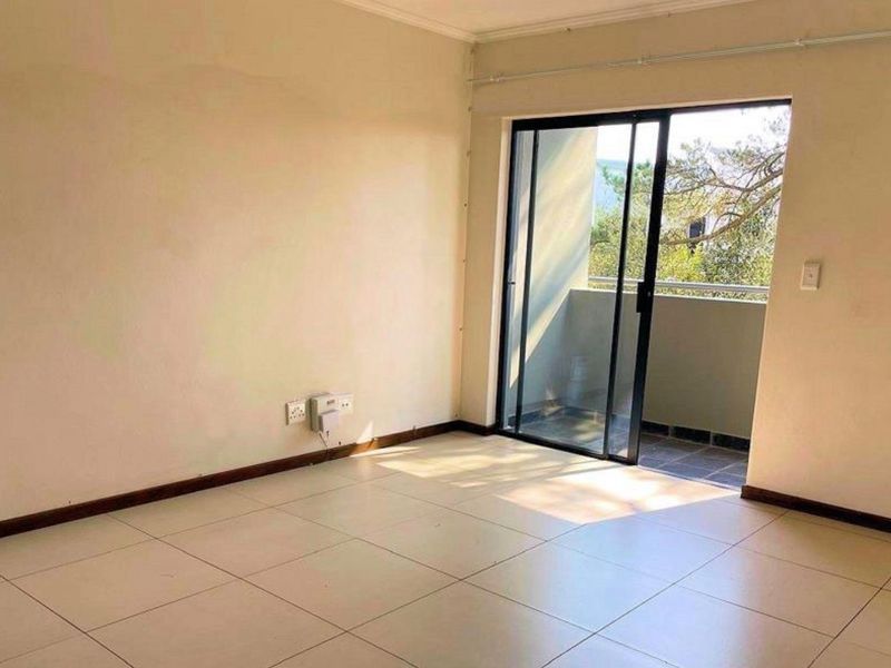 An empty living room featuring tiled flooring and a sliding glass door providing access to an outdoor balcony area.