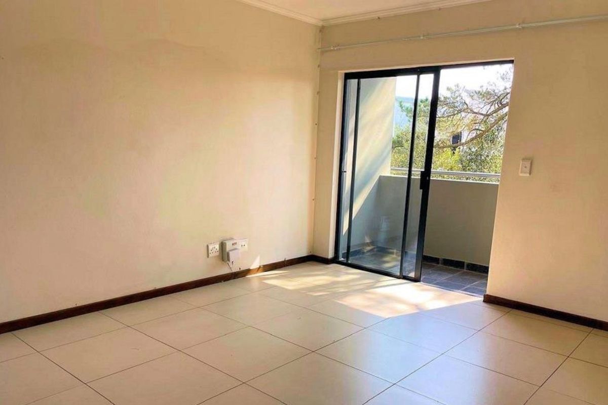 An empty living room featuring tiled flooring and a sliding glass door providing access to an outdoor balcony area.