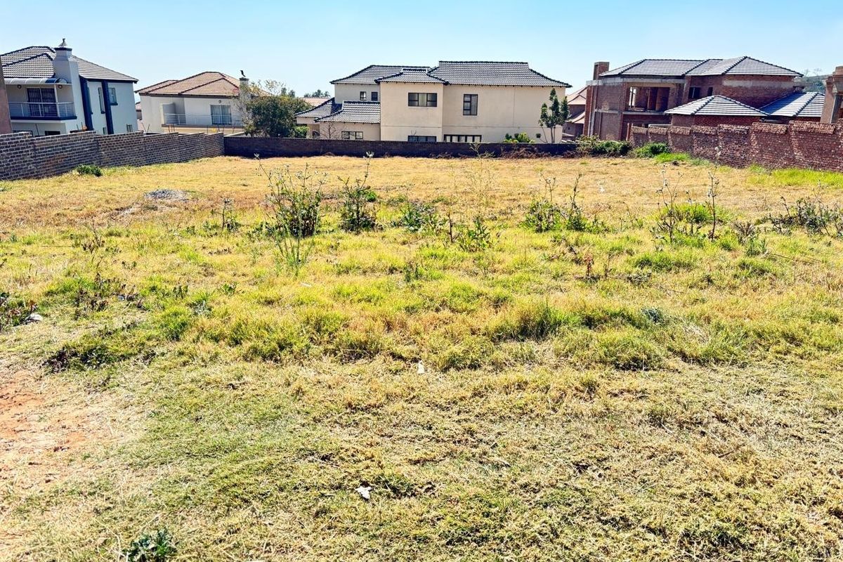 A vacant residential plot featuring a level grass surface enclosed by brick boundary walls, situated within an established residential neighborhood.
