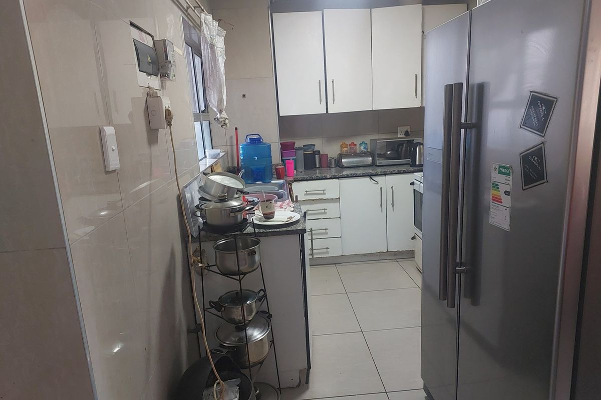 A functional kitchen featuring tiled walls and flooring, built-in cabinetry, and granite countertops, offering a practical layout for daily meal preparation.