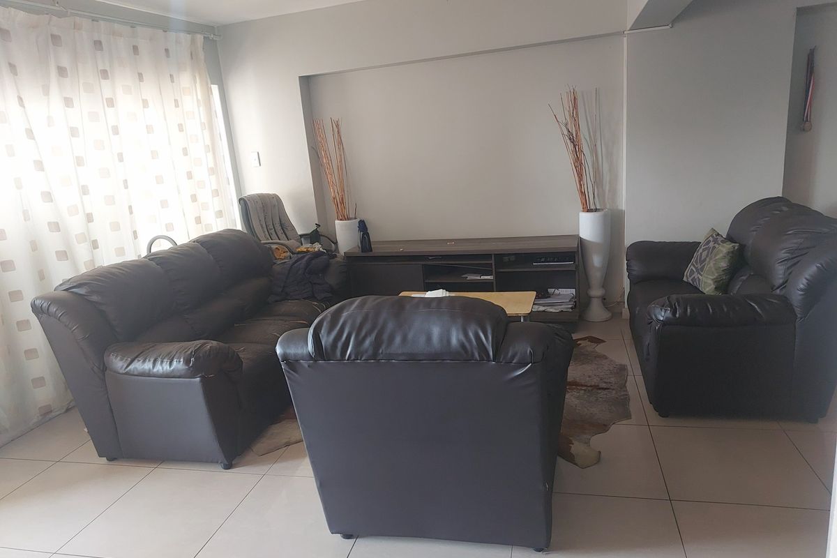A spacious living room featuring neutral tiled flooring and a recessed wall niche, providing a functional and comfortable lounge area.