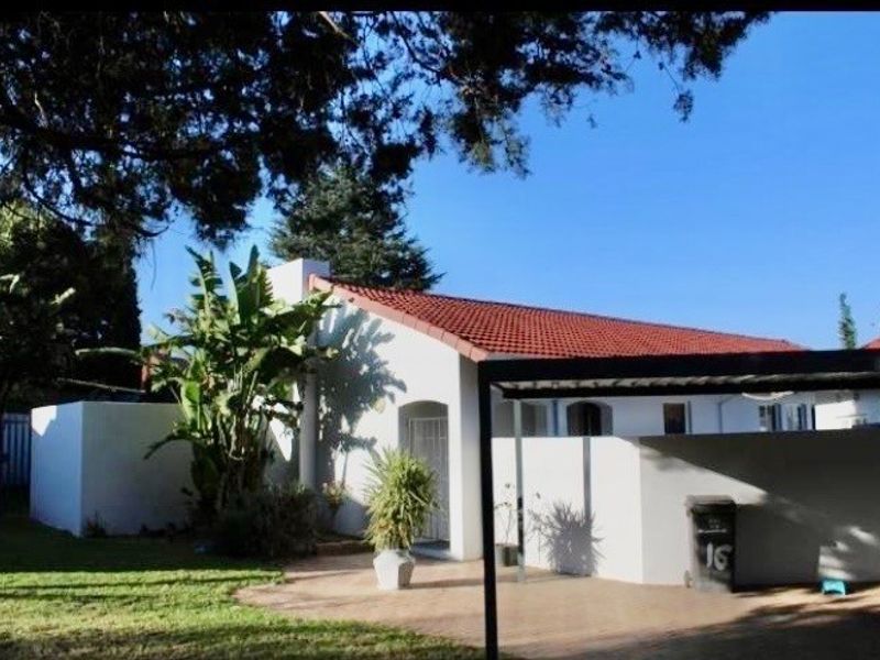Front exterior view of the house featuring a tiled roof, paved driveway area, and a carport structure.