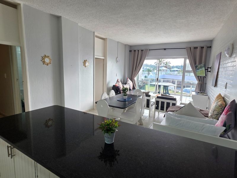 Open-plan living and dining area featuring a granite kitchen countertop, tiled flooring, and direct access to a balcony with exterior views.