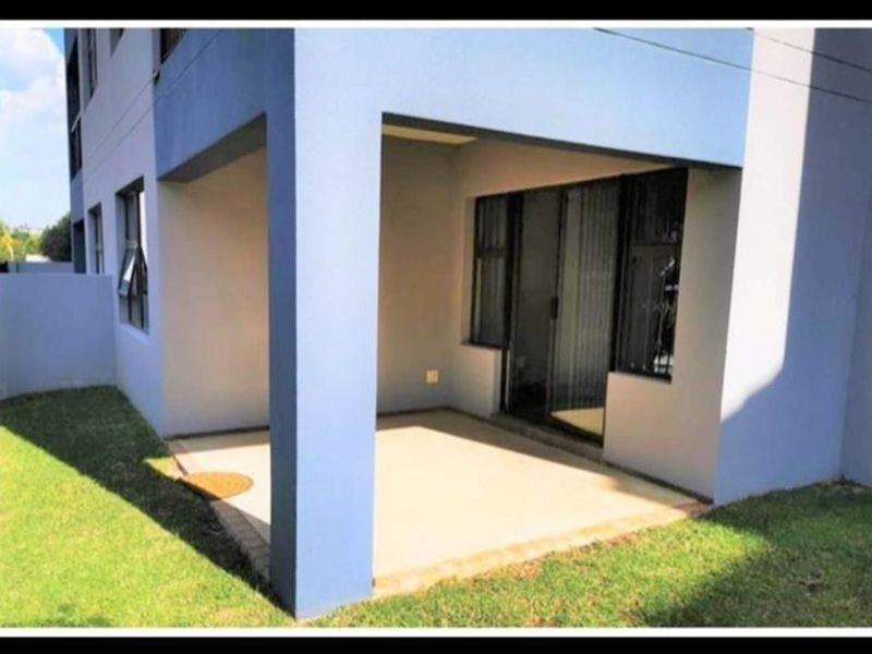 A covered ground-floor patio area featuring a concrete slab and sliding glass door access to the apartment interior.