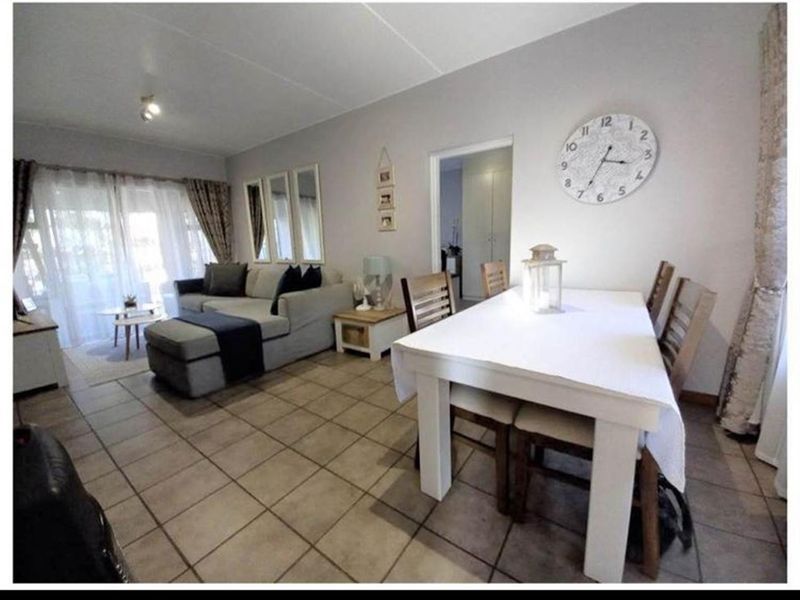 Open-plan living and dining area featuring neutral tiled flooring and a sliding glass door providing access to the exterior.