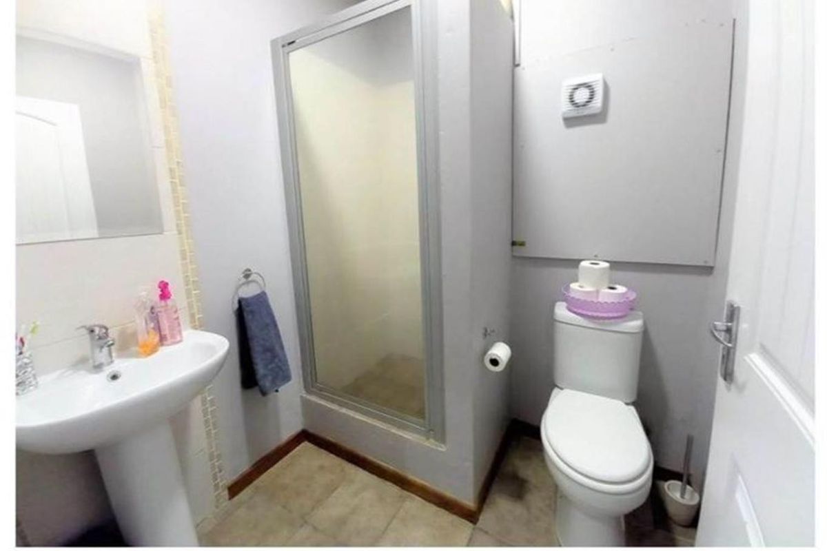 Compact bathroom featuring a pedestal basin, enclosed shower, and toilet, with neutral wall finishes and tiled flooring.