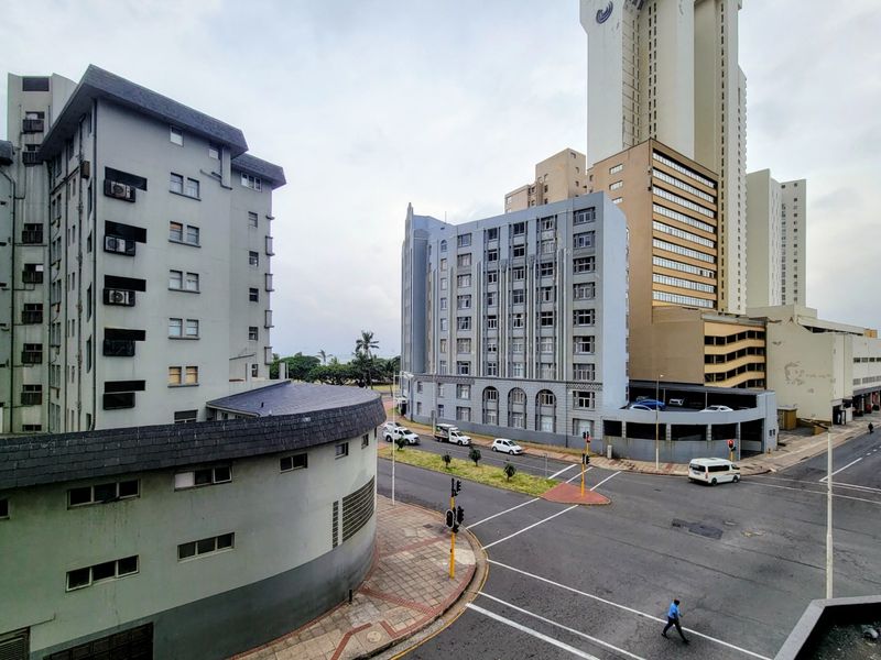 An elevated view of an urban street intersection surrounded by multi-story apartment buildings and city infrastructure.