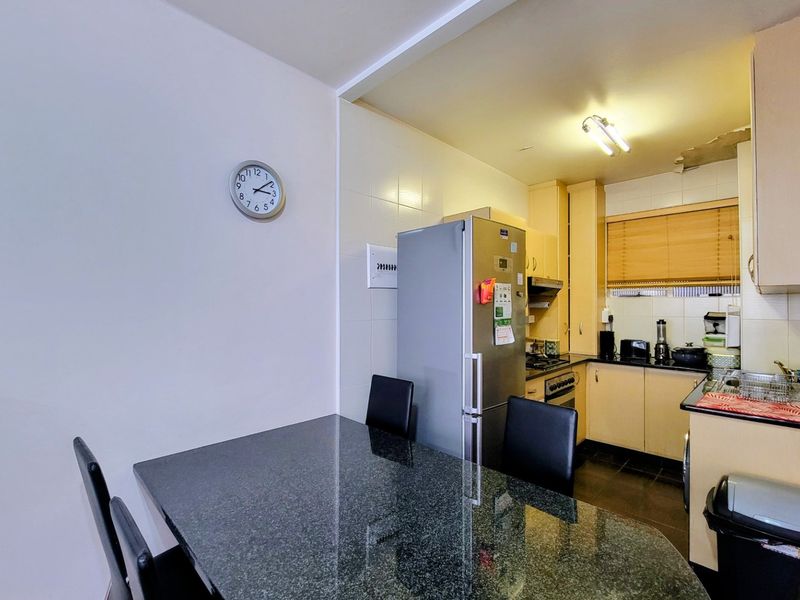 Open plan kitchen and dining area featuring granite countertops, built-in cabinetry, and integrated appliances, with visible ceiling damage requiring repair.