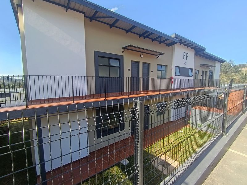 Exterior view of a modern apartment complex featuring a tiled balcony, metal security fencing, and well-maintained building facade.