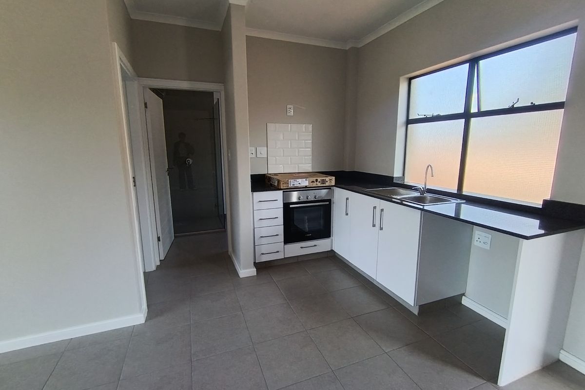 A clean, modern kitchen featuring white cabinetry, granite countertops, a built-in oven, and tiled flooring, offering a functional and neutral space.